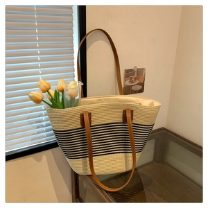 Detailed straw tote bag texture with black stripes and brown leather double handles