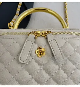 Close-up of diamond quilted leather bag featuring a gold flower emblem and metal handle