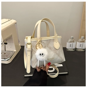 Close-up of gray quilted bucket bag with golden hardware and white plush doll pendant