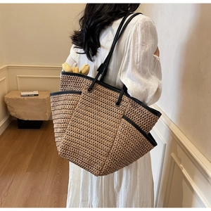 Détail du grand sac cabas en paille avec bordure noire et poches latérales en situation réelle