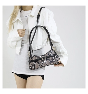 Model wearing a chic snakeskin pattern shoulder bag with a stylish gold buckle accent