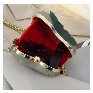 Detail of apple shaped crossbody bag showing red interior and storage for cosmetics
