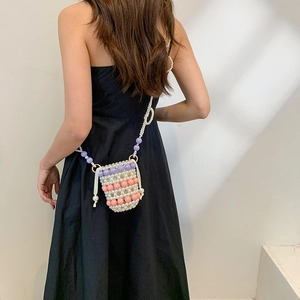 Mini sac à bandoulière en perles tissées main avec détails colorés porté par un mannequin