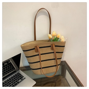 Straw tote bag with black stripes, leather handles and tulip decor on a desk