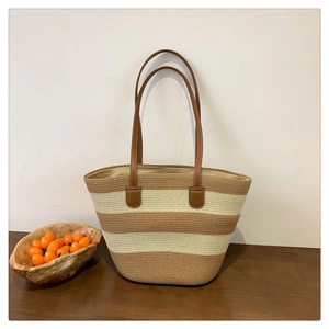 Detail of a large capacity hand-woven straw tote bag with brown and cream horizontal stripes