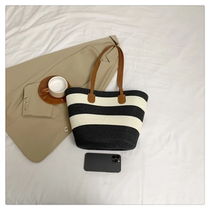 Macro detail of large woven tote bag with black and white stripes and brown handles