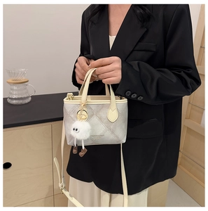 Detail of silver quilted bucket bag with cream handle and cute plush charm on model