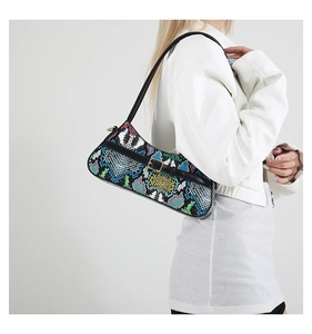 Side view of woman wearing snakeskin pattern baguette bag with adjustable strap