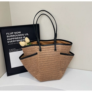 Gros plan du grand sac cabas en paille avec bordure noire et poches latérales pour plage