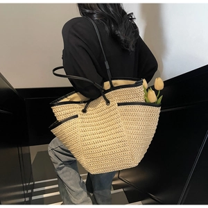 Gros plan d'un grand sac cabas en paille avec lanières en cuir noir et poches latérales