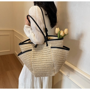 Détail d'un sac cabas en paille tissée beige avec bordure noire et tulipes jaunes