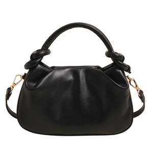 Minimalist black pleated handbag with knotted handle and detachable shoulder strap on white base