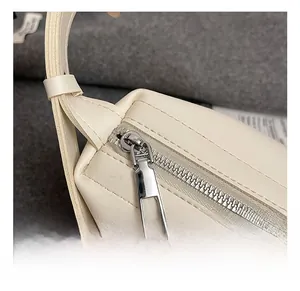 Gros plan sur la fermeture éclair argentée et le cuir PU crème de ce sac sous le bras