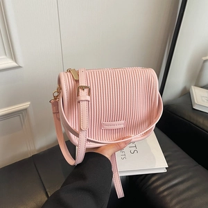 Pink pleated bucket bag with metal fashion tag and adjustable strap in minimalist setting