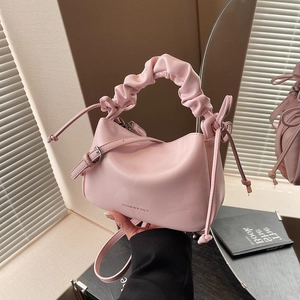 Pink soft leather crossbody bag with pleated handle and fashion text in a mirror view