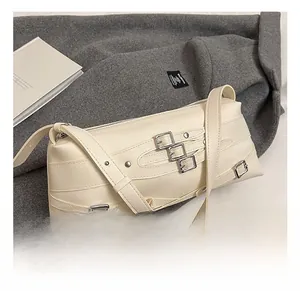 Détail du sac bandoulière en cuir blanc cassé avec boucles argentées et rivets stylés