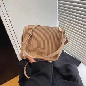 Minimalist beige pleated bucket bag with adjustable strap and fashion label detail