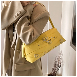 Détail du sac moto en similicuir jaune vif avec boucles métalliques argentées sur blazer beige