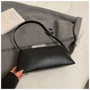Détails macro d'un sac baguette en cuir mat noir avec pieds métalliques et sangle réglable