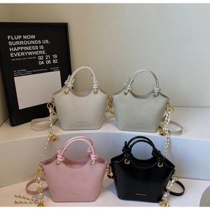 Detail view of bucket bags in beige, green, pink, and black with knotted ring handles