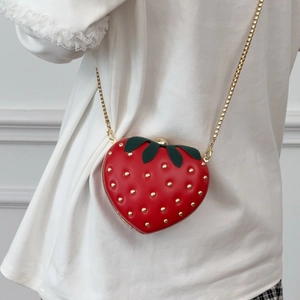 Cute red strawberry shaped crossbody bag with gold rivets and chain strap on model