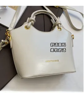 Close-up of cream white bucket bag with golden hardware and adjustable crossbody strap