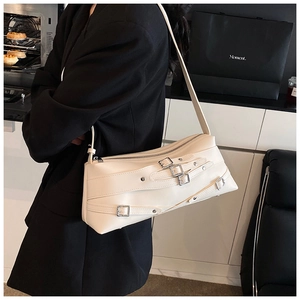 Détail du sac à bandoulière crème avec boucles et rivets argentés porté par un mannequin