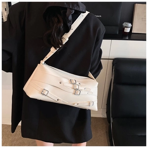 Détail d'un sac à bandoulière blanc crème avec boucles et sangles décoratives argentées