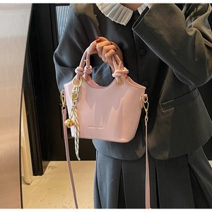Pink PU leather bucket bag detail with striped scarf, bell charm and knot handle