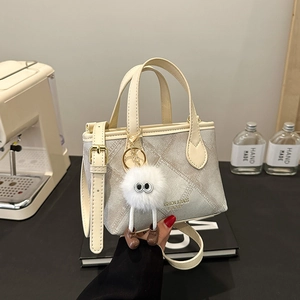 Minimalist light gray canvas bucket bag with leather trim and plush monster charm pendant