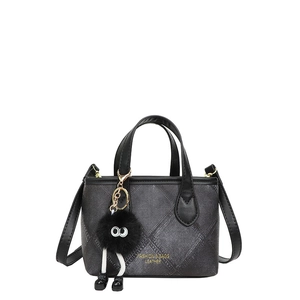 Chic black quilted bucket bag with golden lettering and a plush keychain charm
