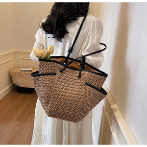 Grand sac cabas en paille pour les vacances d'été avec anses en cuir noir porté par un mannequin