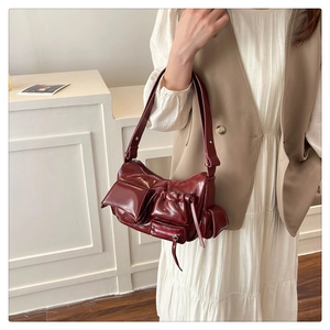 Macro view of burgundy oil-wax leather shoulder bag featuring functional multi-pockets