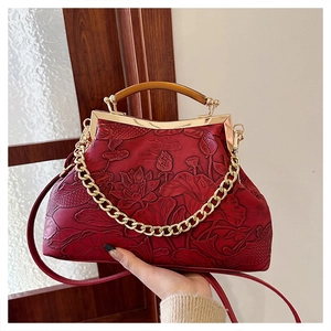 Detail of red embossed vintage handbag featuring lotus and koi relief and gold chain strap