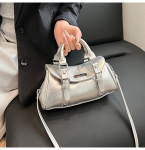 Detail of silver metallic handbag with crinkled texture, top handles, and buckle straps