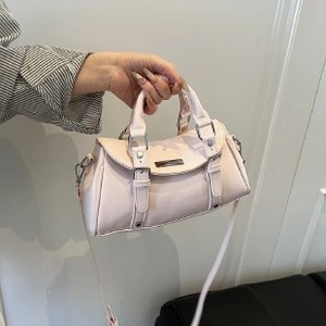 Detail view of pink Boston handbag showing top handles and decorative buckle straps