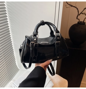 Detail of glossy black Boston handbag with silver hardware and decorative rivets