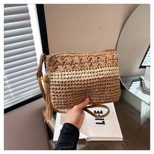 Detail of striped straw bag featuring wooden bead tassel charm and woven texture