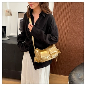 Detail of metallic gold biker bag featuring multi-pocket design and glossy wax leather finish