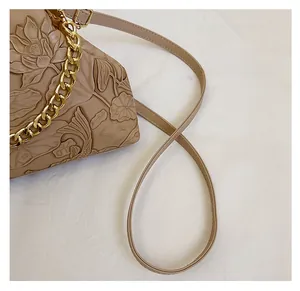 Detailed relief of lotus and koi carp on a beige vintage clutch with golden chain strap