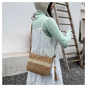 Detail of bohemian straw bag featuring long side tassels and wooden bead accents