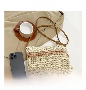 Detail of woven straw crossbody bag featuring striped pattern and brown leather shoulder strap
