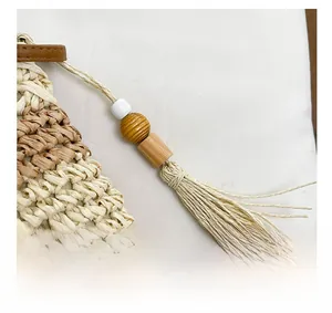 Detail of handmade straw bag featuring tassel charm with wooden beads and white ceramic beads