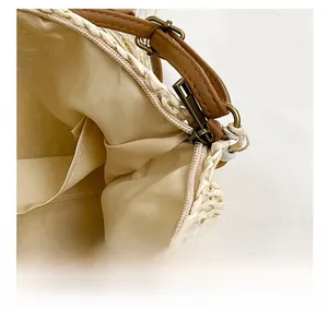 Detail view of straw woven bag with secure metal zipper closure and brown leather strap