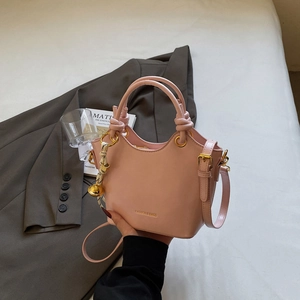 Pink PU leather bucket bag with woven handle and gold hardware on grey suit