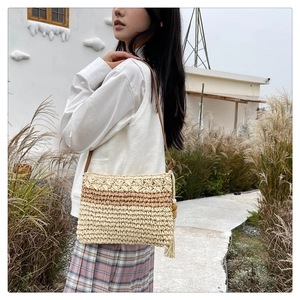 Detail of straw woven bag featuring a stylish tassel and wooden bead charm on shoulder strap