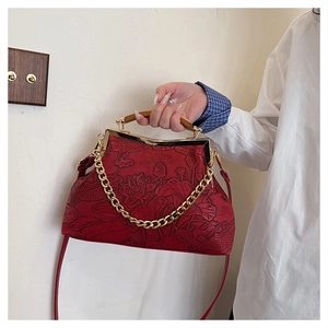 Macro detail of red embossed leather bag with lotus motifs and wooden handle