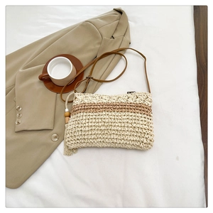 Detail of handwoven straw bag featuring striped design and wooden bead tassel
