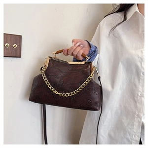 Detail of vintage embossed lotus handbag with wooden handle and gold chain strap