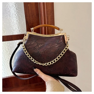 Detail of dark brown vintage evening bag featuring embossed lotus patterns and resin handle